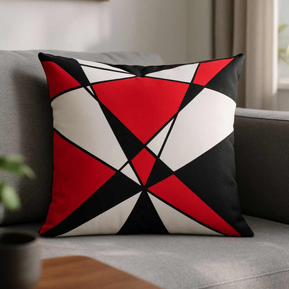 All-Over Print Basic Pillow on a gray sofa, featuring the 3 Colors 2 geometric design with bold red, black, and white angular shapes. Soft indoor light highlights the retro, graphic aesthetic.