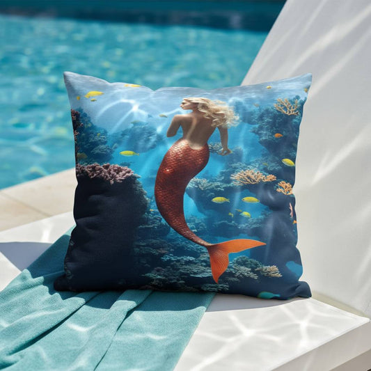 All-Over Print Basic Pillow placed on a poolside chair, featuring the Mermaid design with a swimming mermaid, coral reefs, vibrant fish, and deep blue underwater tones. The scene highlights the aquatic theme in bright natural light.