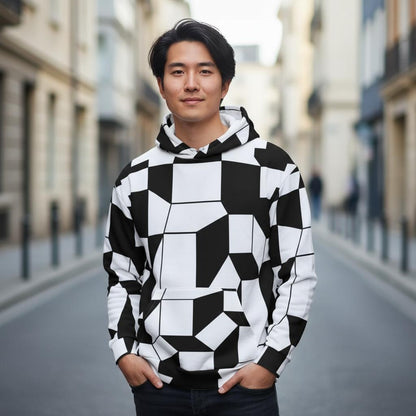black and white geometric facettes pattern hoodie worn by a young man standing in a bright urban street modern sixties inspired design with bold shapes and clean lines detailed fabric texture visible on sleeves and hood all over print unisex hoodie shown clearly for product presentation