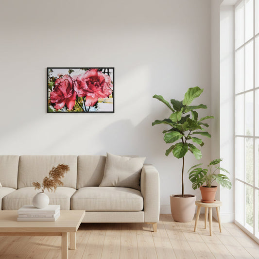 Framed poster Two Roses displayed above a beige sofa in a bright minimalist living room, showing two vivid red and pink blossoms with detailed petals. Natural daylight from large windows enhances the floral artwork and the soft, elegant home decor.