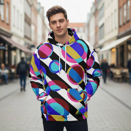 colorful retro circle pattern hoodie with overlapping blue pink gold and turquoise shapes worn by a young man standing in a bright urban street all over print design with bold sixties inspired graphics soft fabric texture visible on sleeves and hood modern artistic style shown clearly for product presentation