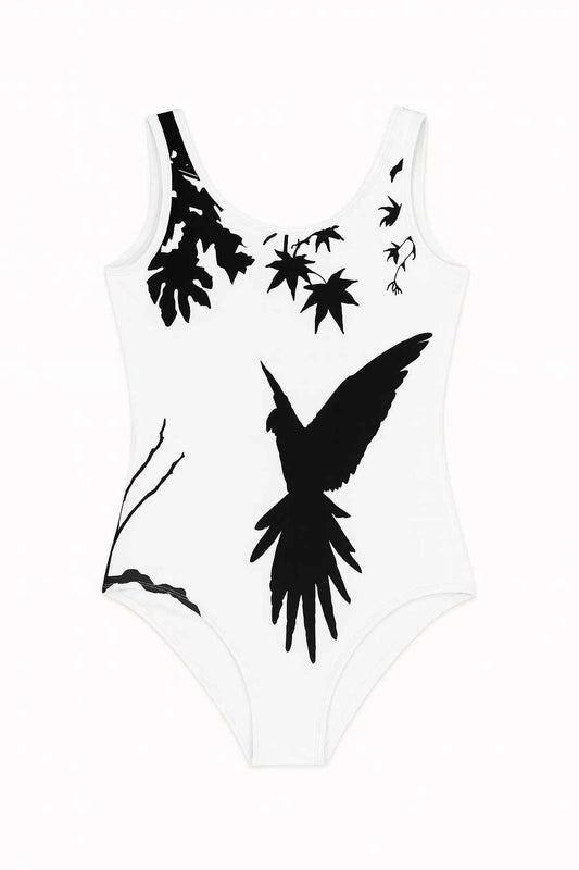 Kids swimsuit with black parrot silhouette on white background, artistic nature design showing leaves and branches, minimalist bird illustration flat lay on neutral surface