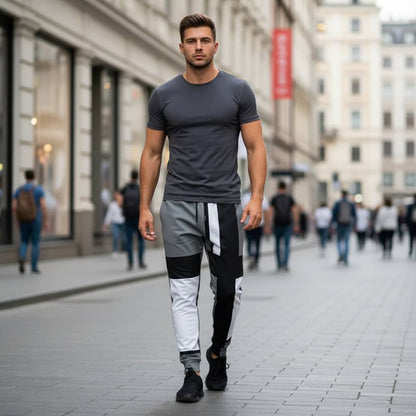 men’s joggers with 60s inspired geometric design in black white and grey, slim fit recycled joggers worn by model walking in modern city street, minimalist retro pattern with clean angular blocks and contemporary streetwear style