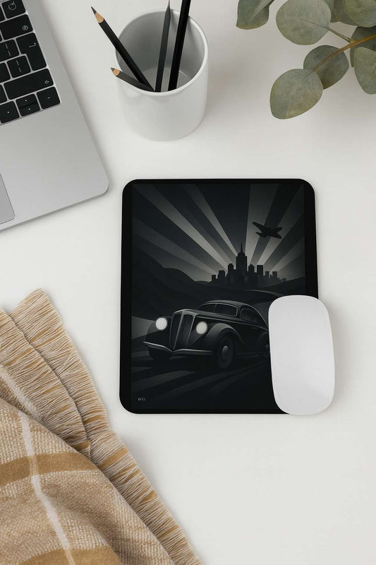 A vertical mouse pad featuring a monochrome Art Deco scene with a vintage car speeding toward a city skyline and an airplane above, placed on a white desk beside a laptop, a white mouse, a pencil holder, a plant and a plaid cloth.