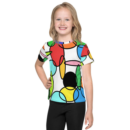 Child wearing a colorful Kids T-Shirt with Chain abstract retro design inspired by 60s and 70s art, showing circular linked shapes in bright tones, photographed outdoors near a playground in natural daylight.