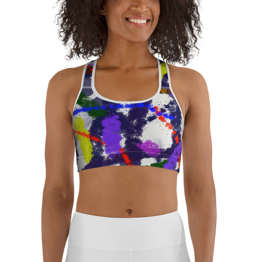 Woman wearing a colorful abstract art sports bra featuring bold paint splash design in purple, red, green, and yellow on a white and black background.